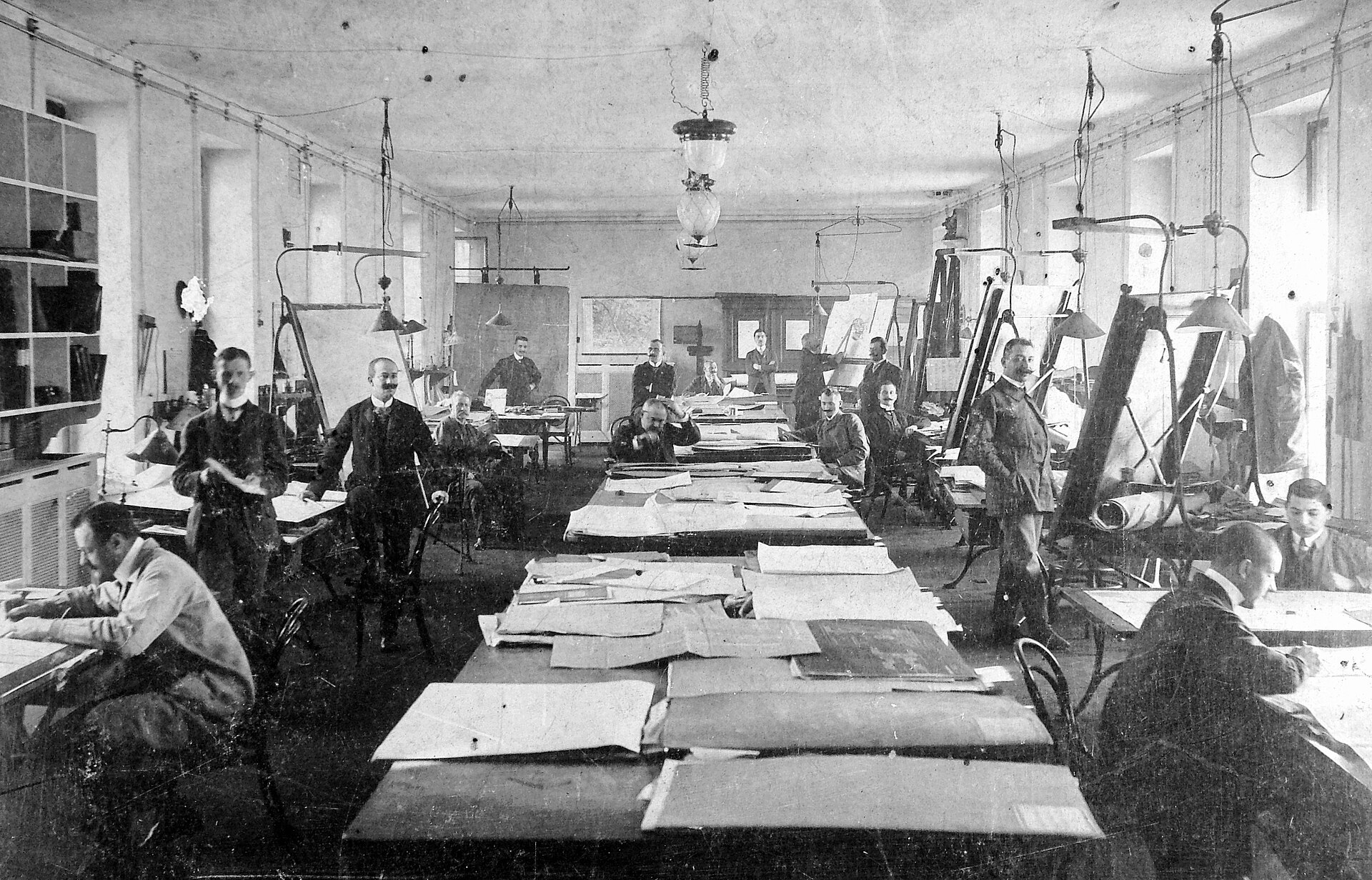 An archival technical drawing room with people working at drafting tables in 1918.
